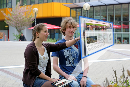 Studenten, junge Frau und junger Mann, vor Projektionsfläche